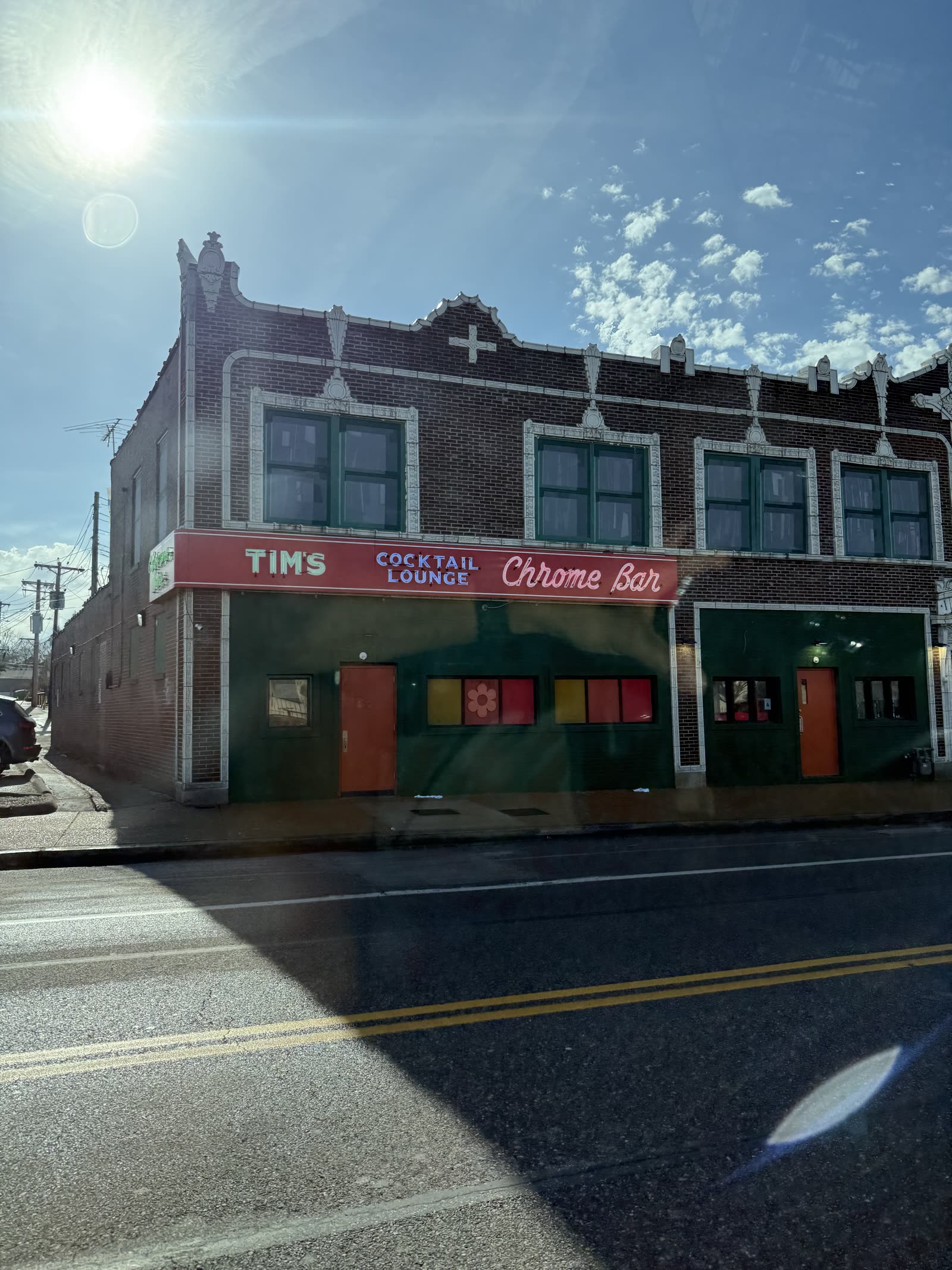 A single-storey brick bar on a street corner in daylight, its sign reading Tim's Cocktail Lounge Chrome Bar.