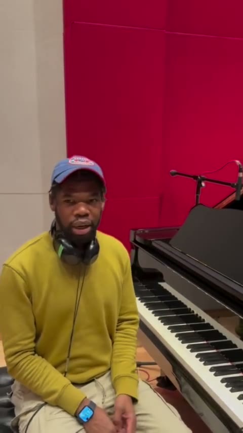 Lordell Rush at the studio's grand piano in headphones, talking through the score.